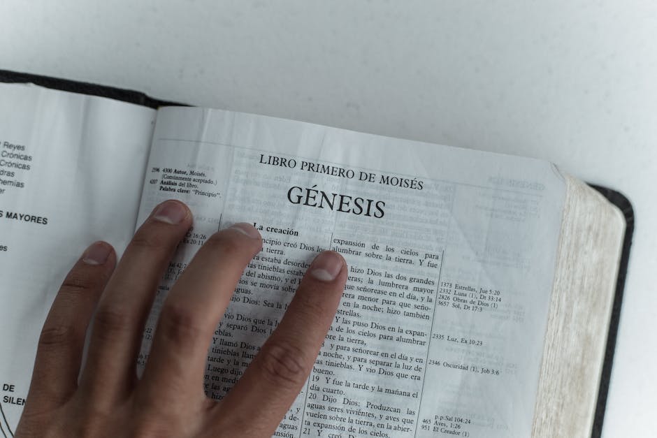 Close view of Genesis chapter in Spanish Bible, hand touching page.