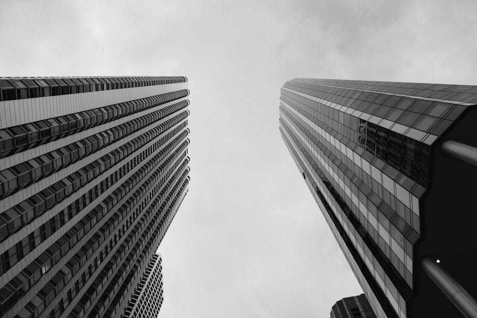 Dramatic view of towering skyscrapers reaching into a cloudy sky, captured in black and white.