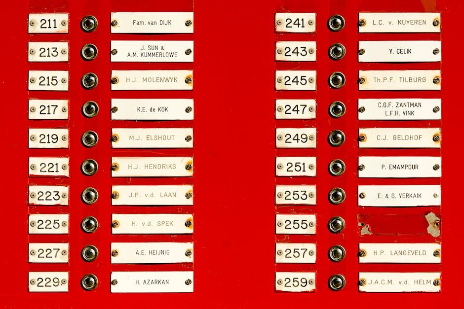 Close-up of a red doorbell panel with multiple nameplates and buttons in a building.