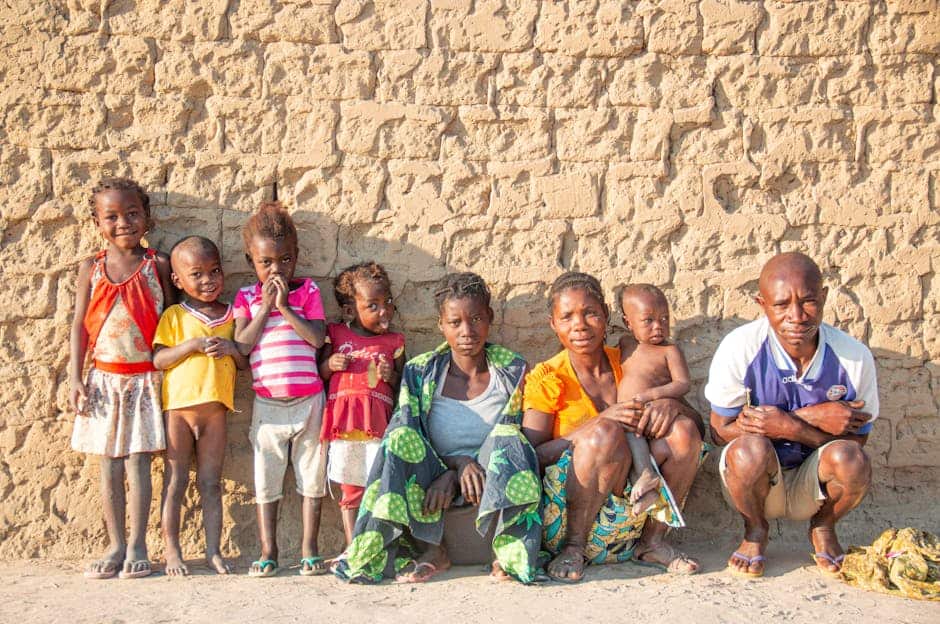 A family poses together against a rustic stone wall in Cuando Cubango Province, Angola.