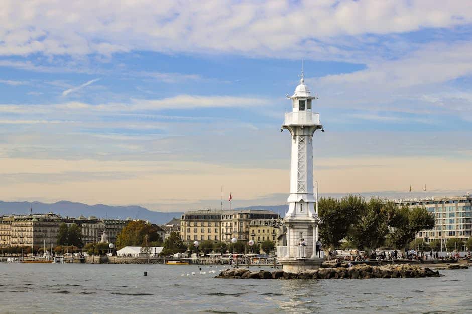 Scenic view of lighthouse by Lake Geneva with cityscape in the background.