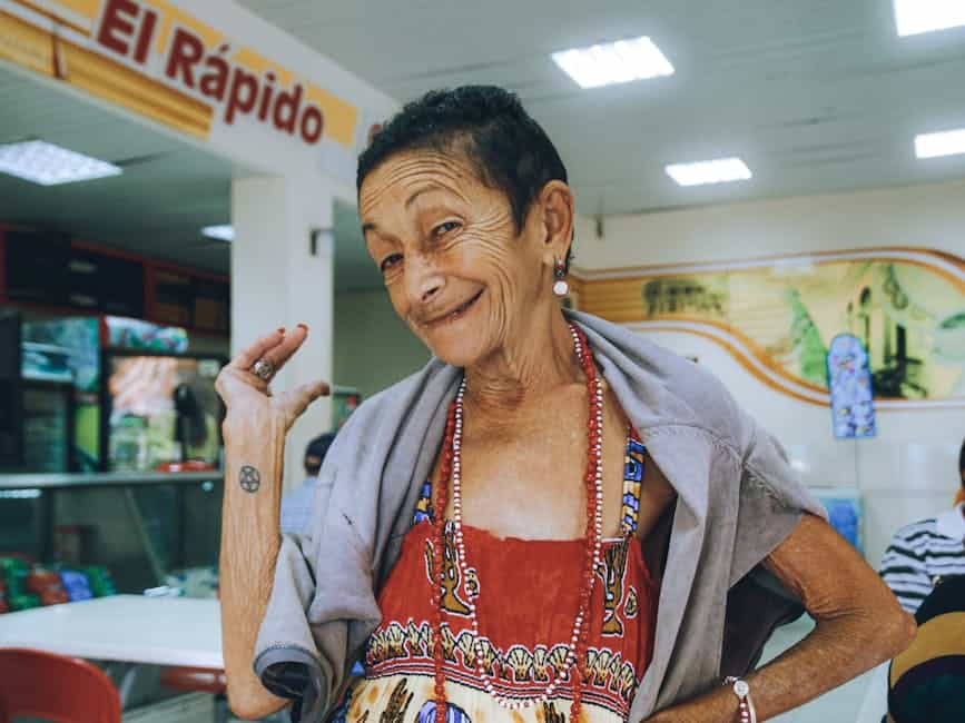 Portrait of a smiling senior woman in vibrant clothes at a cafe.