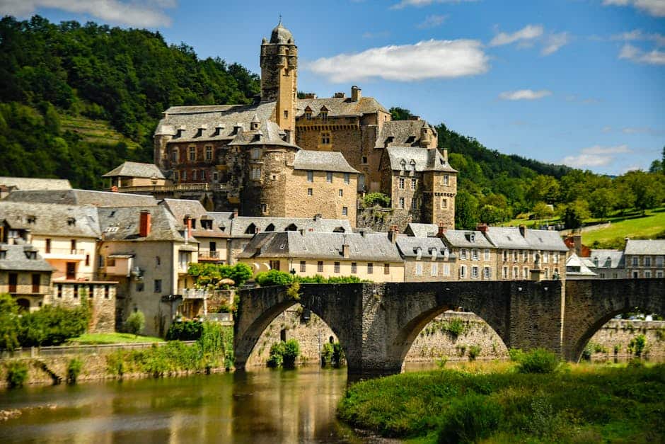 Picturesque castle and bridge in Estaing, France, surrounded by village and nature.