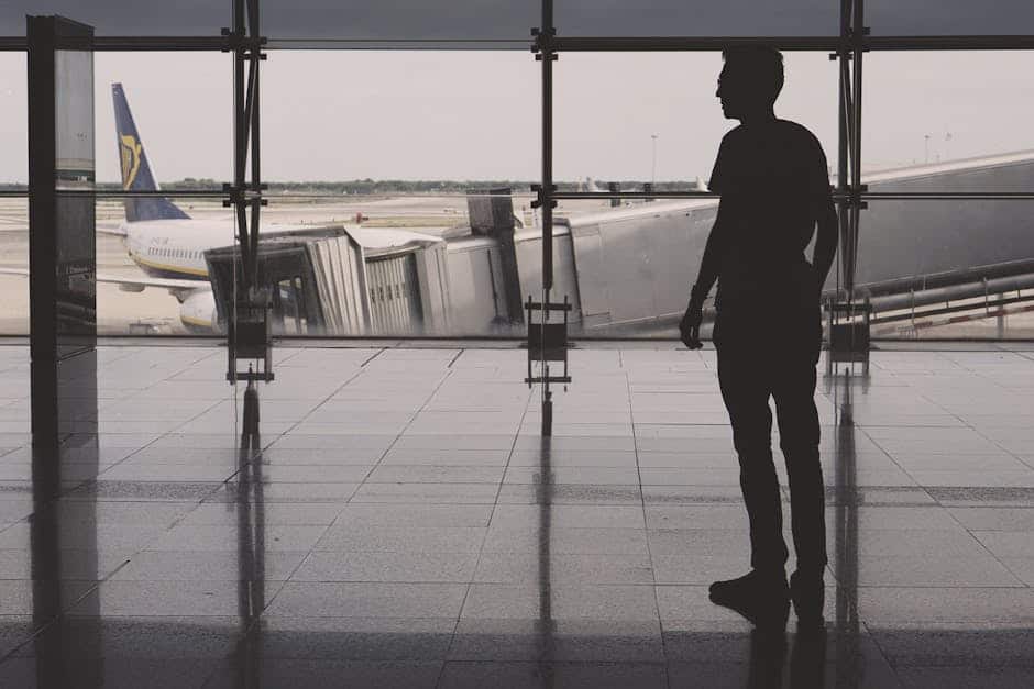 Silhouette of a man at El Prat airport with airplane reflections on glass walls.