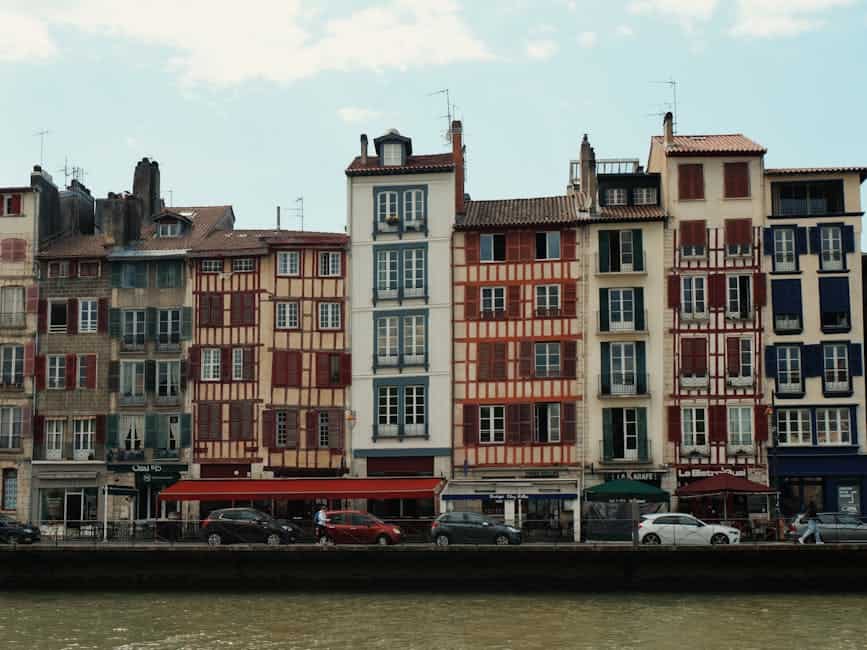 Charming traditional buildings along the Nive River in Bayonne, France, showcasing unique Basque architecture.