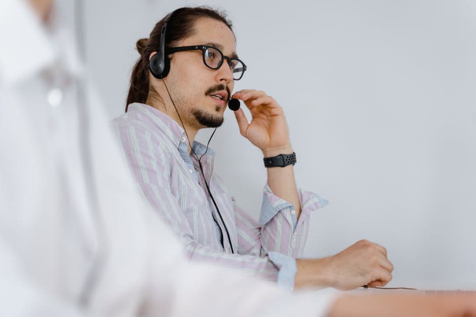Focused customer service agent speaking on a headset in a modern office environment.